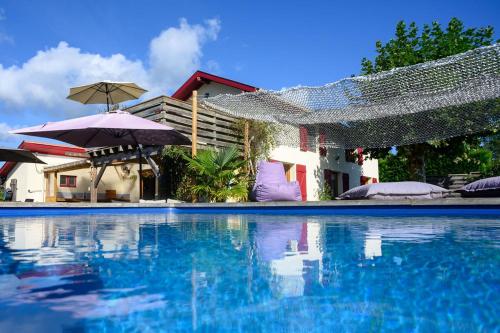 una piscina con agua azul y sombrillas en The Secret Spot Lodge, en Azur