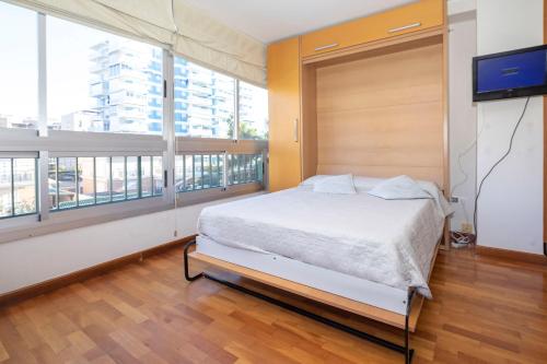 a bedroom with a bed and a flat screen tv at Bonito apartamento en la playa in Benicàssim