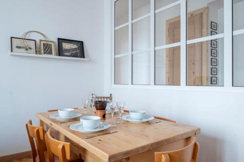 une table en bois avec des assiettes et des verres au-dessus dans l'établissement Nice Apt With Balcony In Chamomix, à Chamonix-Mont-Blanc