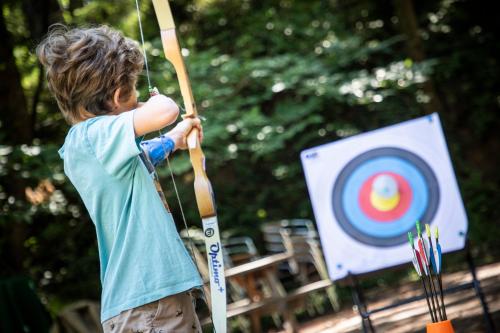 a young boy holding a bow and arrow in front of a target at Huttopia Royat in Royat