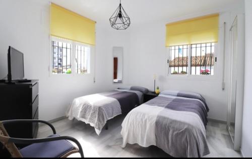 a bedroom with two beds and two windows at Apartamentos Nerjaplaya in Nerja