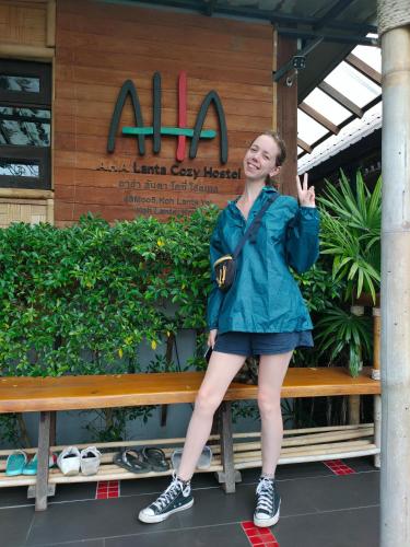 a woman sitting on a bench in front of a store at Aha Lanta Cozy Hostel in Ko Lanta
