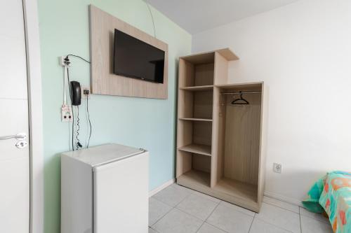 a room with a tv and a closet with a door at Xangri-La Praia Hotel in Xangri-lá