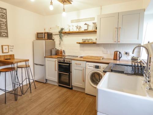 a kitchen with white cabinets and a sink and a dishwasher at Pengeulan in Machynlleth
