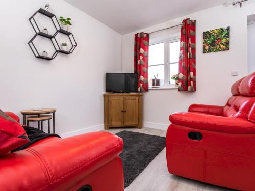 a living room with a red couch and a tv at 2 Bedroom Home Near the Heart of Ludlow - Pass the Keys in Ludlow