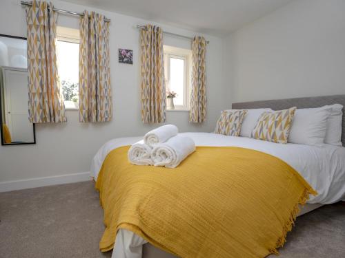 a bedroom with a bed with a yellow blanket and windows at Pass The Keys Stylish brand new two bedroom house, close to town in Ludlow