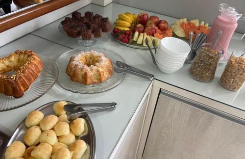 a counter topped with plates of pastries and fruit at Xangri-La Praia Hotel in Xangri-lá