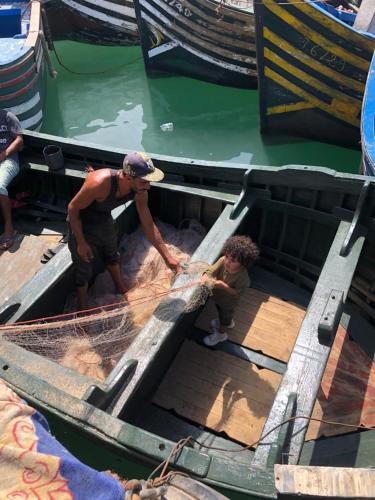 two men working on a boat in the water at Appartement Maroc Safi in Safi