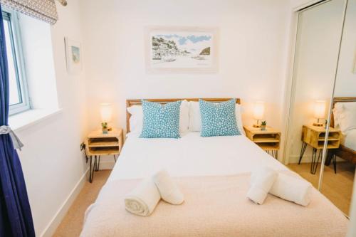 a bedroom with a large white bed with blue pillows at Sunset Waves Sea view apartment featuring panoramic views & parking in Newquay