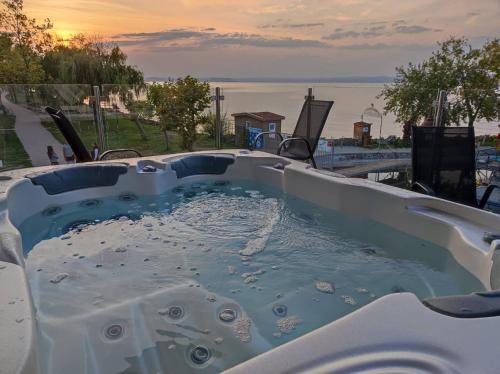 a jacuzzi tub with a view of the ocean at Calypso Lakeside Rooms & Lux Apartments in Siófok