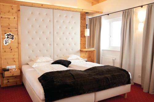 a bedroom with a large white bed with a blanket at Hotel Enzian Hochsölden Superior in Sölden