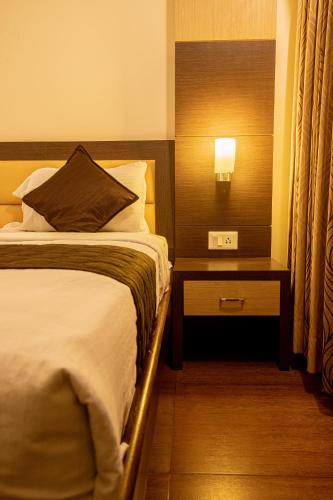 a hotel room with a bed and a night stand with a lamp at Sri Krishna Palace in Hosūr