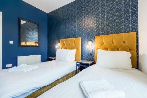 two beds in a room with blue walls at Queen Street Apartments by Sasco in Blackpool