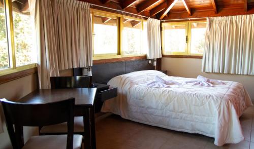 1 dormitorio con cama, mesa y ventanas en Piedras Doradas Hotel y Spa en Valeria del Mar