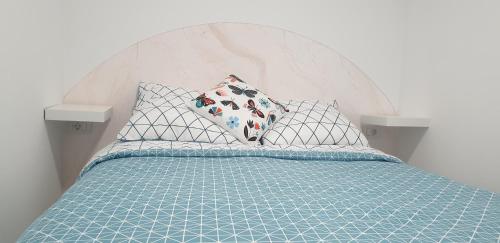 a bed with a blue comforter and two pillows at Playa del Ingles. Apartamento al lado del océano in San Bartolomé de Tirajana