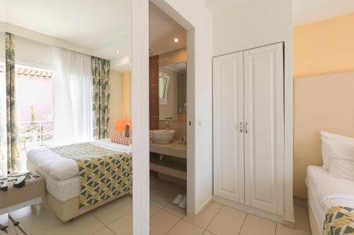 two images of a bedroom with a bed and a bathroom at Mandraki Village Boutique Hotel in Koukounaries