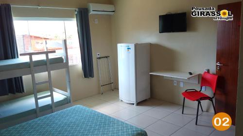 um quarto com um frigorífico, uma secretária e um beliche em Pousada Girassol da Ferrugem em Garopaba