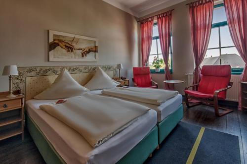 a hotel room with two beds and two red chairs at Hotel zur Henne in Naumburg