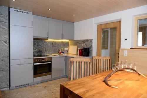 a kitchen with white cabinets and a wooden table at Gästehaus Flöry in Schruns-Tschagguns