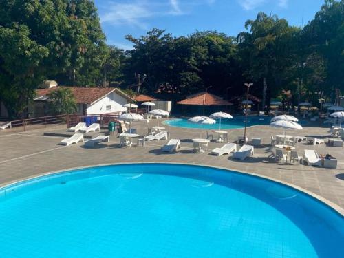 a swimming pool with chairs and tables and umbrellas at Hotel Sesi Aruana in Aruanã