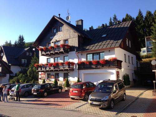 a building with cars parked in a parking lot at Pension and Apartments MONIKA in Špindlerův Mlýn