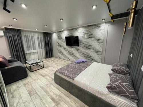 a bedroom with a bed and a tv on a wall at Люкс академика сатпаева 19 in Pavlodar