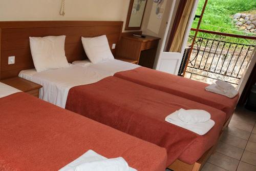 a hotel room with two beds and a balcony at Castri Hotel in Delfoi