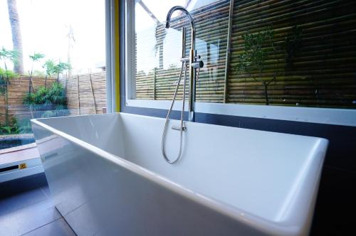 a white bath tub in a bathroom with a window at 墾丁海芋 獨棟泳池Villa - 訂房後需聯繫轉帳, 才有完成訂房 in Hengchun