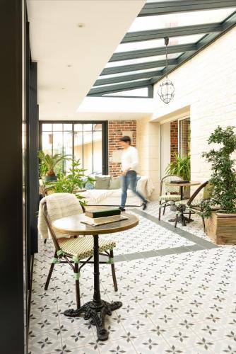 a man is walking on a patio with a table at Les Glycines de Monchy- Chambres d'hôtes in Monchy-Humières