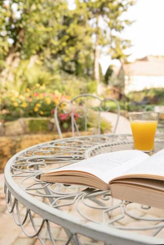 a table with two books and a glass of orange juice at Les Glycines de Monchy- Chambres d'hôtes in Monchy-Humières