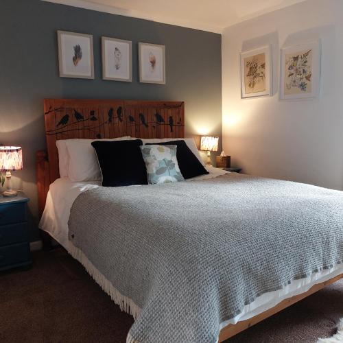 a bedroom with a large bed and some pictures on the wall at Foxglove Cottage in Clearwell