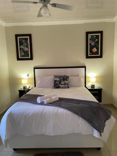 a bedroom with a large white bed with two lamps at Mohlakeng Guest House in Randfontein