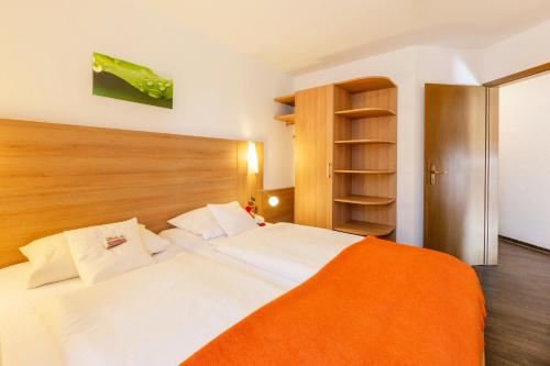a bedroom with a large white bed with an orange blanket at Hotel Engel - Familotel Hochschwarzwald in Todtnauberg