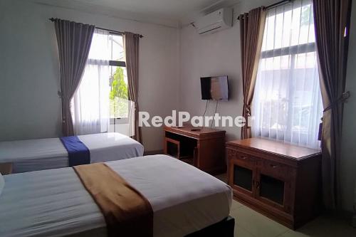 a hotel room with two beds and a television at Hotel Abna Sangatta Mitra RedDoorz in Sengata