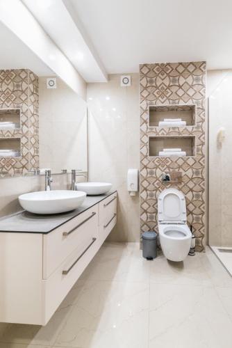 a white bathroom with two sinks and a toilet at Daisy resort in Novi Sad