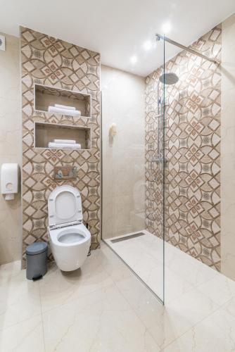 a bathroom with a toilet and a glass shower stall at Daisy resort in Novi Sad