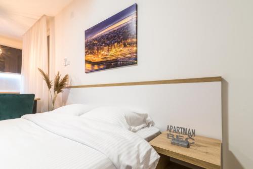 a bedroom with a white bed with a picture on the wall at Daisy resort in Novi Sad
