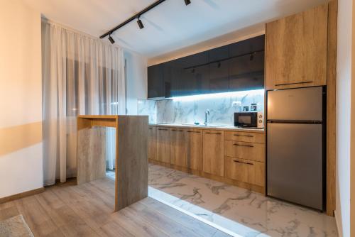 a kitchen with wooden cabinets and a refrigerator at Daisy resort in Novi Sad