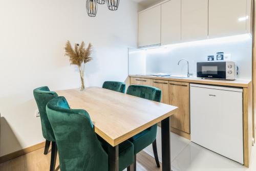 a kitchen with a wooden table and green chairs at Daisy resort in Novi Sad