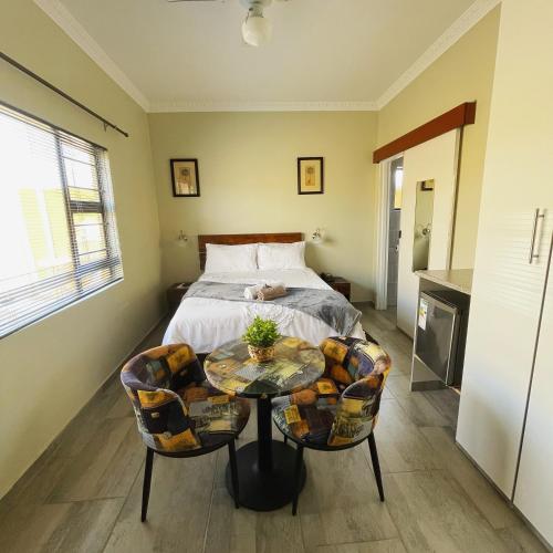 a bedroom with a bed and a table and chairs at Mohlakeng Guest House in Randfontein