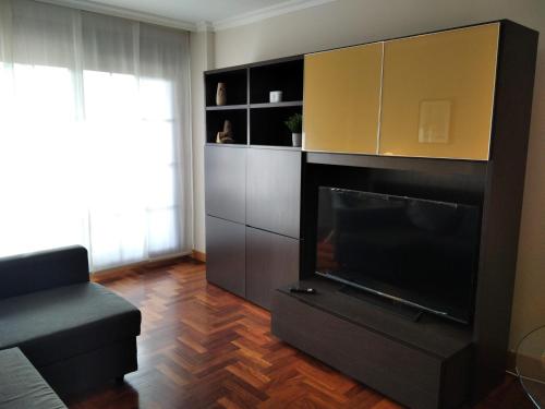 uma sala de estar com uma televisão grande e um sofá em JARDINES DE VINJOY em Oviedo