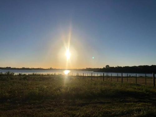 einen Sonnenuntergang über einem Feld mit einem Zaun und einem See in der Unterkunft Bitcoin's House II. Laguna Brava in Corrientes