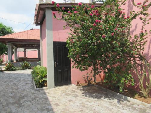 a pink house with a black door and a bush with pink flowers at Villa à Odza borne 12 Aéroport a 10min in Yaoundé