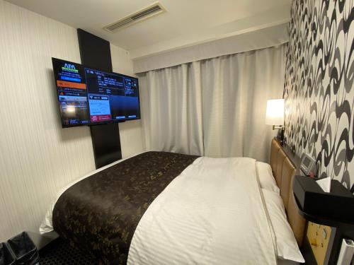 豊橋市にあるアパホテル〈豊橋駅前〉のベッド1台、薄型テレビが備わるホテルルームです。
