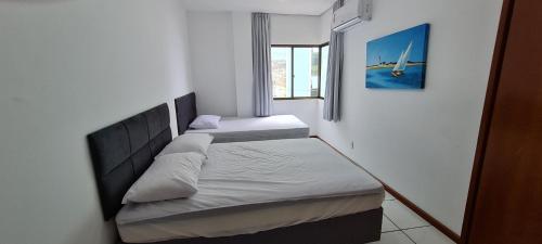 Un dormitorio pequeño con dos camas y una ventana. en Apto em prédio frente ao mar, Meia Praia Itapema, linda vista, 3 dormitórios, en Itapema