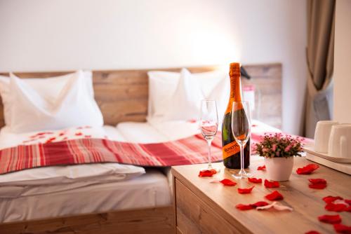 a bedroom with a bed with a bottle of wine and glasses at Pensiune Rara Paltinis in Păltiniş