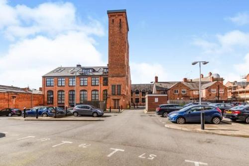 a parking lot with cars parked in front of a brick building at Leicester River Building Ensuite King size Luxury Bed in Leicester