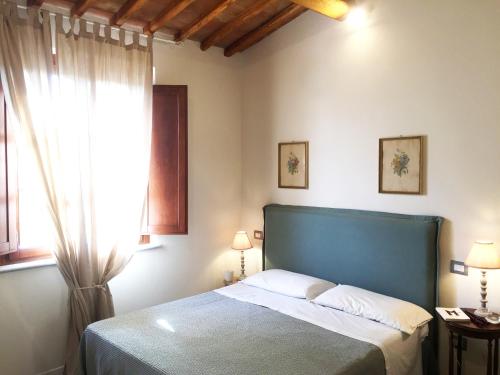 - une chambre avec un lit doté d'une tête de lit bleue et d'une fenêtre dans l'établissement Oliveta del Verde Appartamento con Grande Giardino 500mt dal Centro, à Sienne