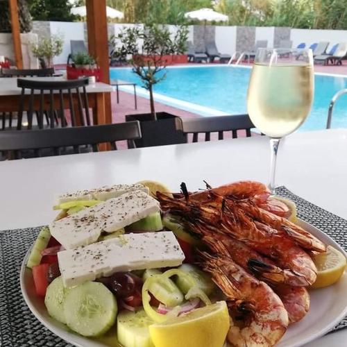 a plate of food with seafood and a glass of wine at Platoni Elite Villas in Ialyssos