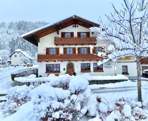 una casa cubierta de nieve delante en HAUSZEIT APPARTEMENTS, en Haus im Ennstal